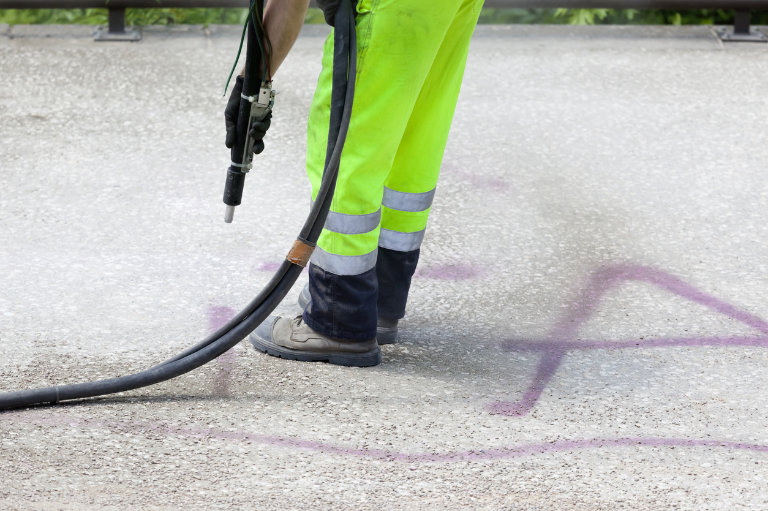 Arbeiter entfernt Graffiti mit Hochdruckreiniger.